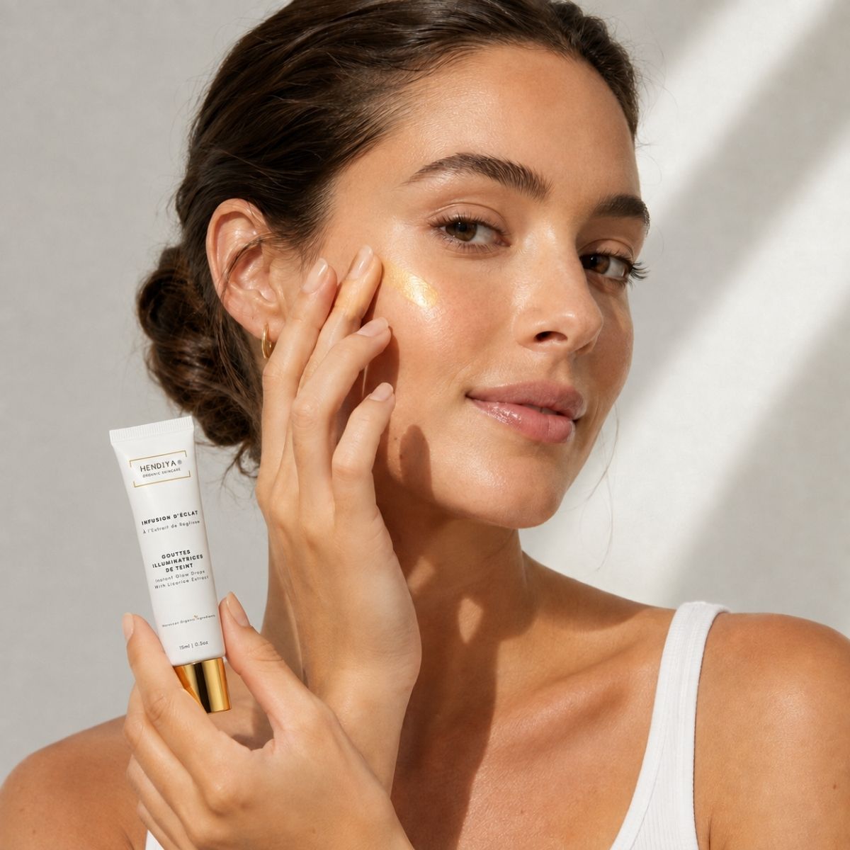Applying Infusion d'Éclat to the face, natural highlighter by Hendiya®